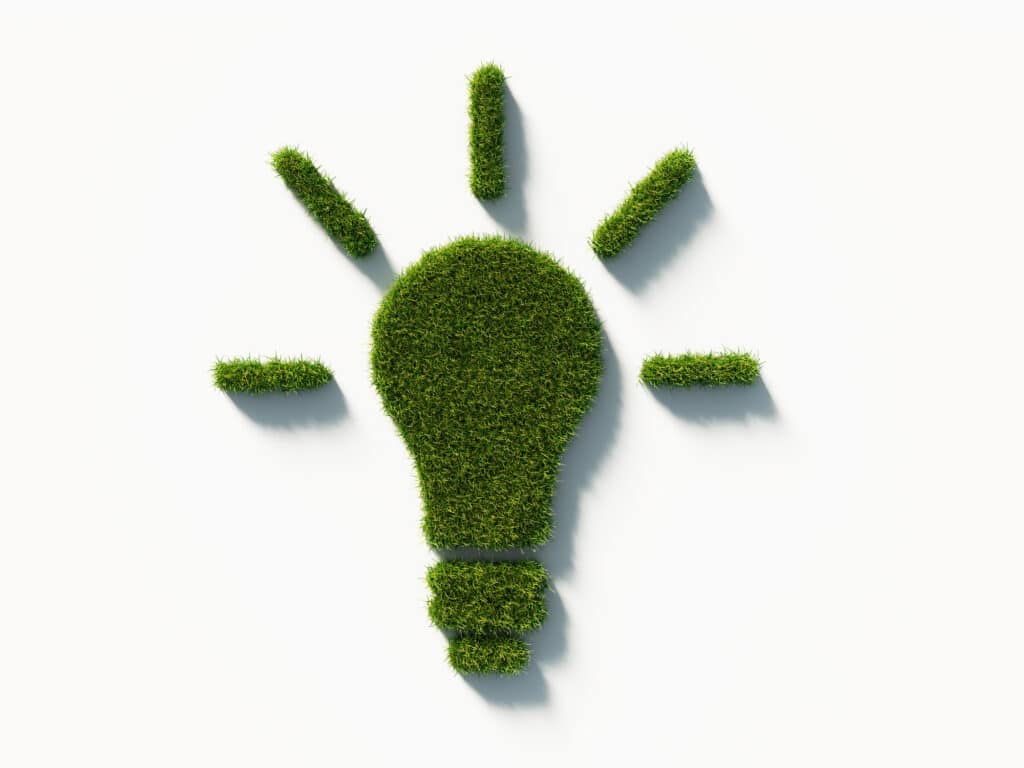 A light bulb symbol made of green grass on a white background, symbolizing eco-friendly tree removal.