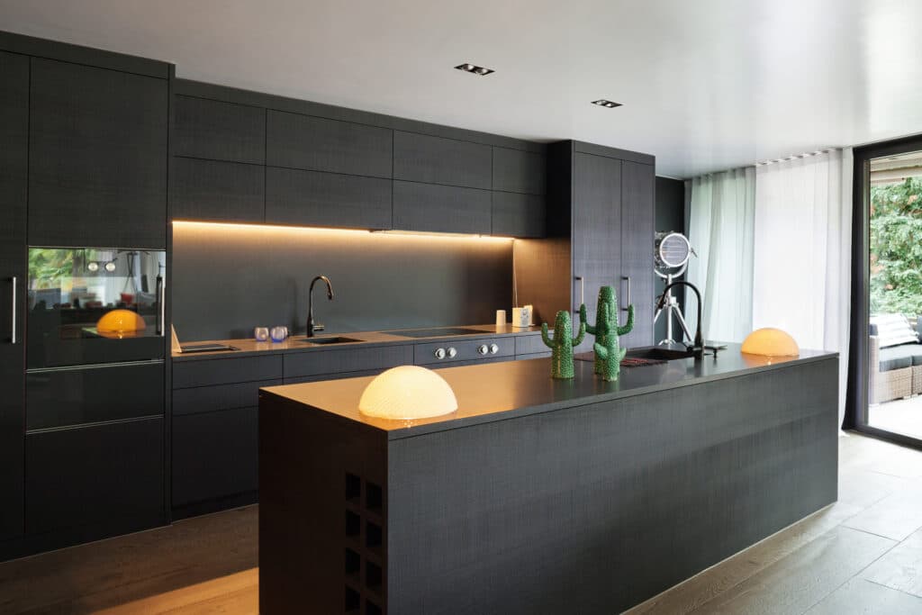 Modern kitchen featuring black furniture and wooden flooring. Kitchen Remodeling by Mana Home Services